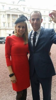Martin holding his OBE medal with his wife Lara outside Buckingham Palace.